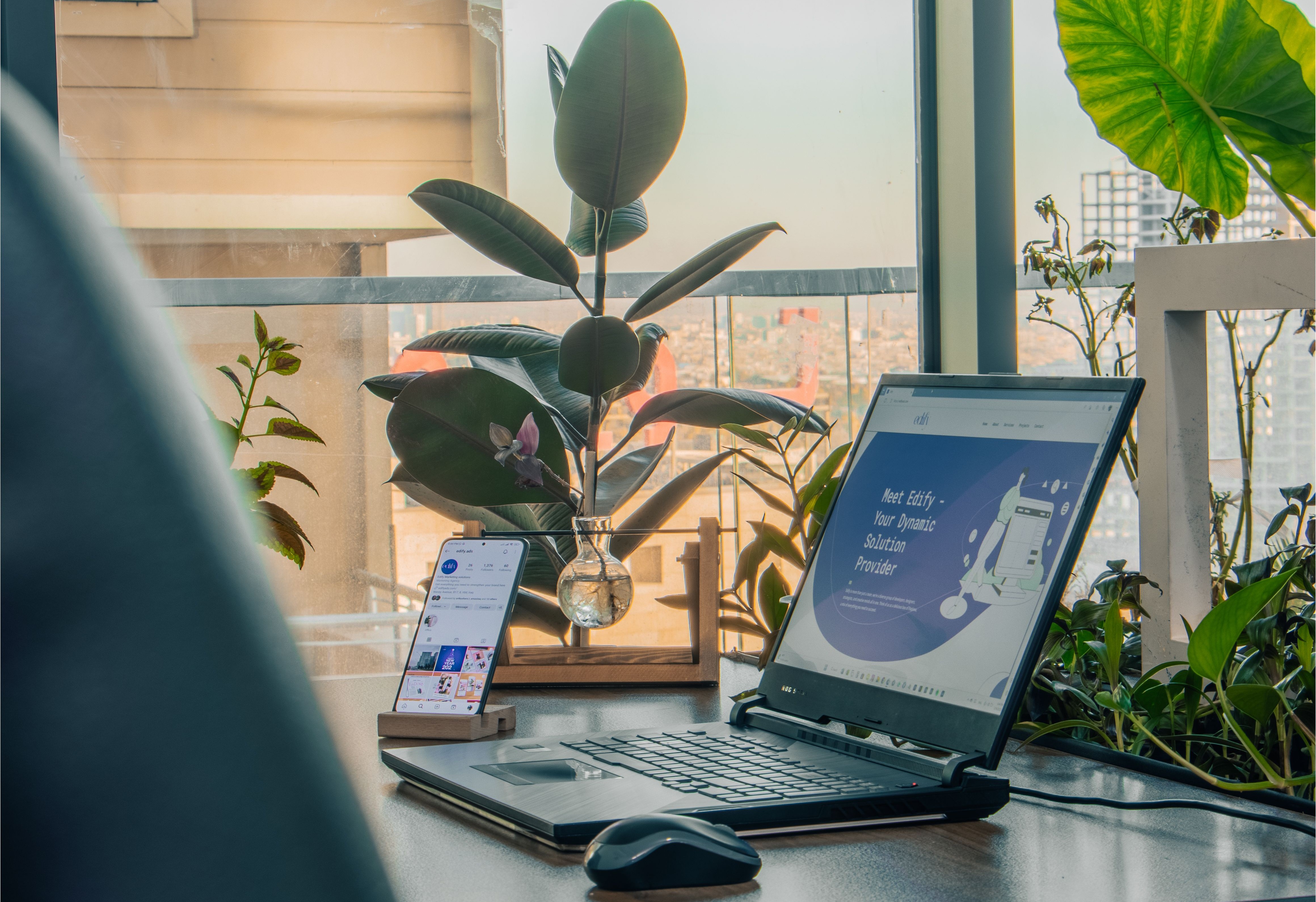 Lyst kontor med laptop, planter og utsikt
